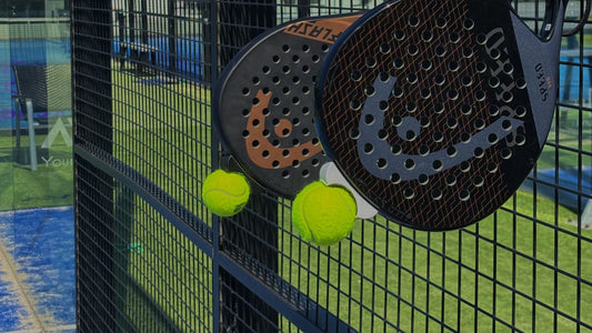 Twee Padel Rackets hangend aan het hek met een bal die in de padelgrab vast zit